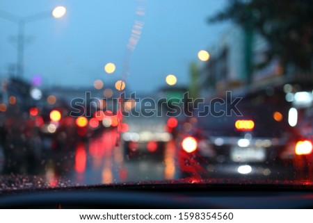 traffic jam on night road city with storm rainy day weather, car driving on street town with water rain drop on windshield outside of bad view