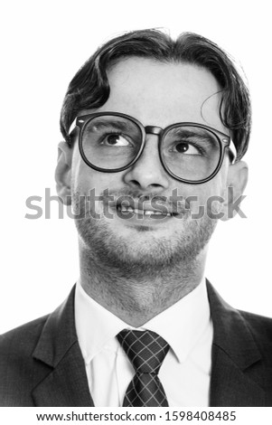 Face of young happy businessman smiling wearing eyeglasses while thinking and looking up