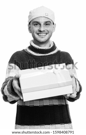 Studio shot of young happy man smiling while giving gift box