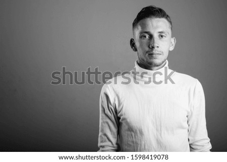 Young man wearing white turtleneck sweater against gray background