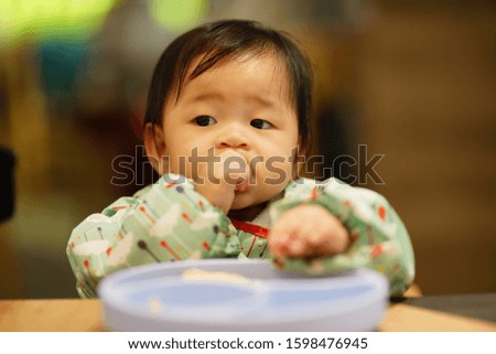 Asian baby is eating food in the restaurant.