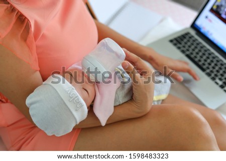 businesswoman breastfeeding milk her baby and working with laptop computer in home business office, image of single mother with supermom concept