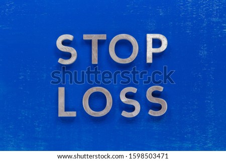 The phrase stop loss laid on blue painted board with thick silver metal aphabet characters.
