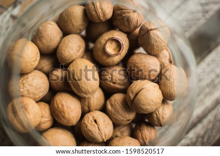 Aquarium with walnuts and wedding rings standing on the table. Transparent and spherical glass. Gold precious metal. Wooden smooth surface. Reflection in the form. Screensaver for your desktop.