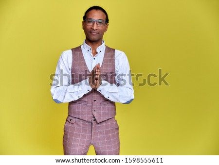 Portrait of a young African American man with short haircuts and a white-toothed smile in a business suit on a yellow background. Standing and talking right in front of the camera.