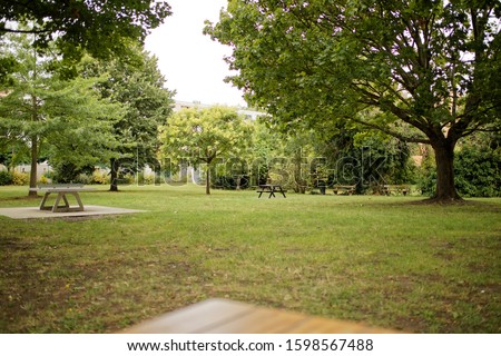 Trees in a city park view with  grass benches and buildings in palaiseau france george sand park near paris during a summer day 