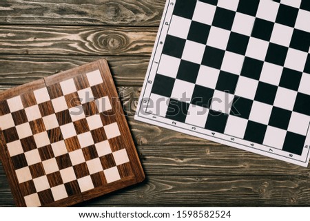 Top view of two chessboards on textured wooden background