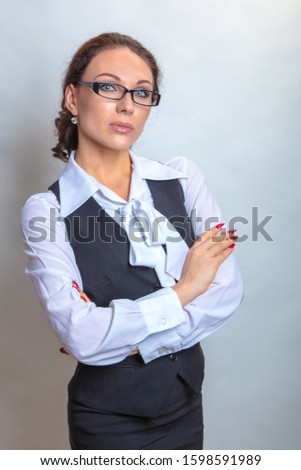 Beautiful businesswoman in glasses with arms crossed, in a white blouse and vest, on a white background