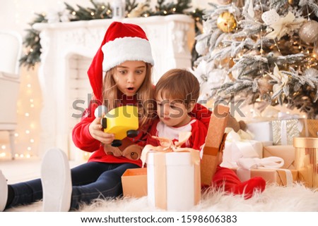 Little children opening Christmas gifts at home
