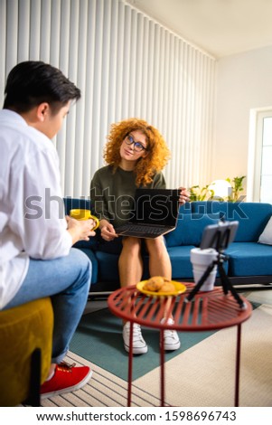 Pretty lady talking with man while recording an interview indoors stock photo
