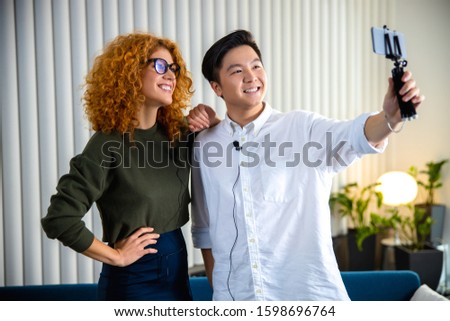 Smiling Asian guy using mobile phone while posing stock photo
