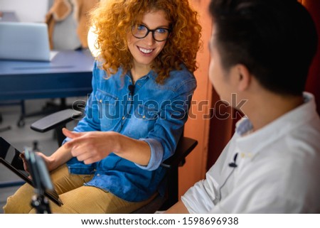 Smiling man with smartphone talking with pretty female colleague stock photo