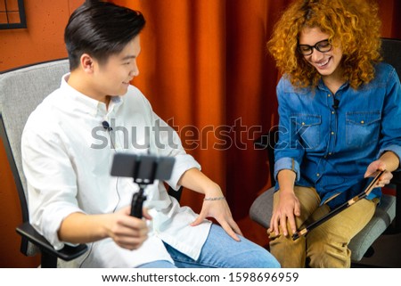 Happy pretty woman holding tablet while showing it for guy in the office stock photo