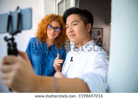 Asian guy holding mobile phone while making video stock photo