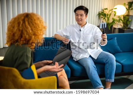 Smiling man making video while looking at lady and enjoying coffee stock photo