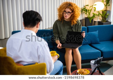 Pretty lady with laptop while while recording interview with guy in the office stock photo