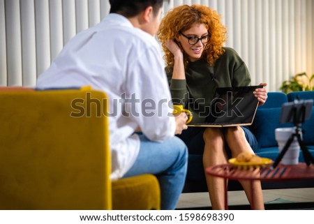 Happy beautiful female recording an interview with guy in the office stock photo