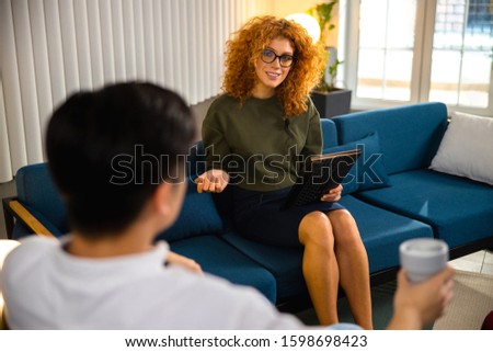 Happy young lady using laptop and looking at man in the office stock photo