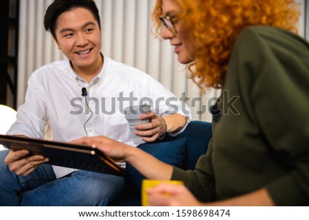 Smiling guy enjoying hot drink while talking with female blogger stock photo