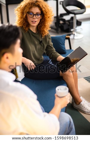Beautiful woman chatting with Asian man while recording an interview stock photo