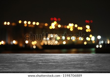 Empty grey stone surface and blurred view of night city. Bokeh effect 