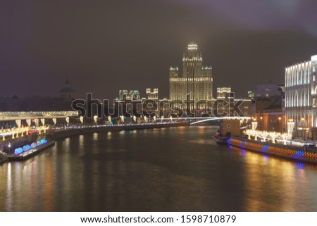 Photography of Stalinist skyscraper on Kotelnicheskaya embankment and Observation Deck Zaryadye Park in winter night. The spire hiding in the fog. International touristic concepts.