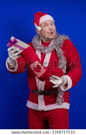 Santa Claus holds a lot of gift boxes and packages in his hands