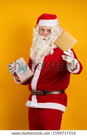 Santa Claus holds a lot of gift boxes and packages in his hands