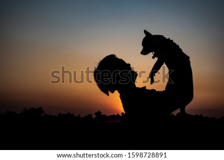 Happy time of little dog with his owner and beautiful sunset sky,dogs is best friend of human. Silhuoette concept.