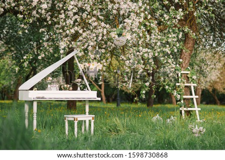 White Grand piano and white staircase with romantic decor in spring in a blossoming Apple tree garden Royalty-Free Stock Photo #1598730868