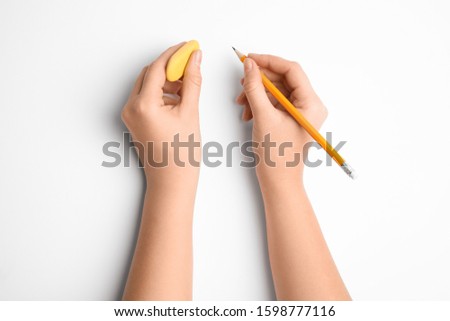 Woman holding pencil and eraser on white background, top view