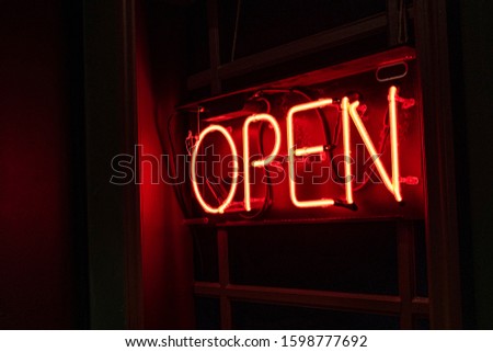 Red neon OPEN sign at an angle in a window at the end of a dark and mysterious hallway leading to a secret location known to few.