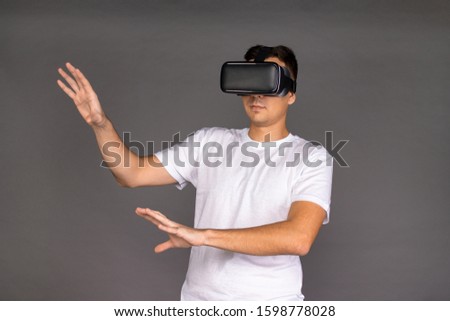 A guy in virtual reality glasses is studying his surroundings. Future and modern technologies. Image on a gray background.