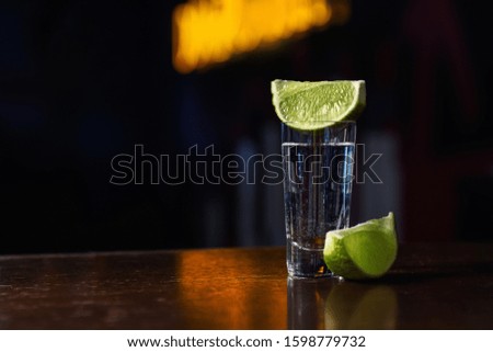 Mexican Tequila shot with lime slices on wooden bar counter. Space for text