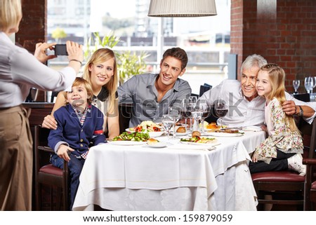 Grandmother taking family picture in restaurant with her smartphone
