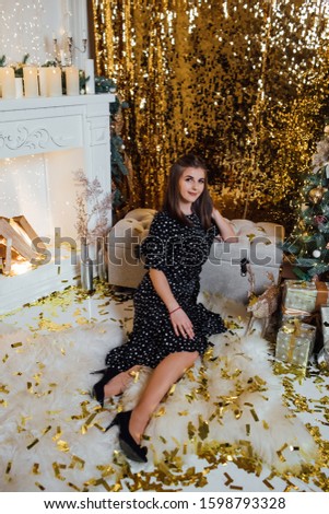 Christmas photo. Smiling young woman in a festive dress with a Christmas gifts and Christmas tree. Happy New Year 2020. Holidays, celebration and people concept - young woman in elegant dress 