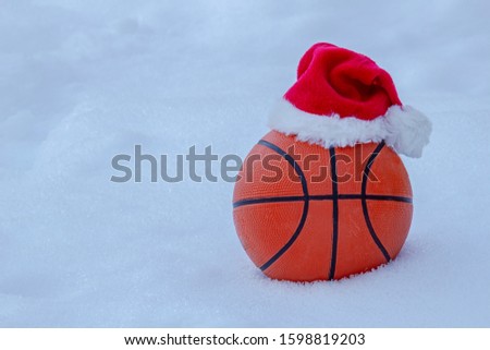 Basket ball wearing a santa hat on snow during winter
