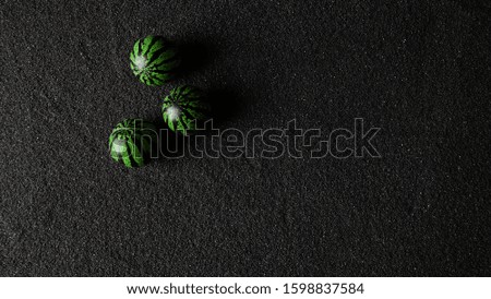 Green watermelon toy on the black sand beach background