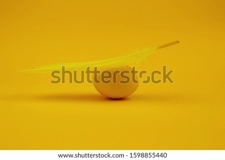 Easter single-colored egg and feather on yellow background. Happy Easter greeting card. Minimal easter concept.