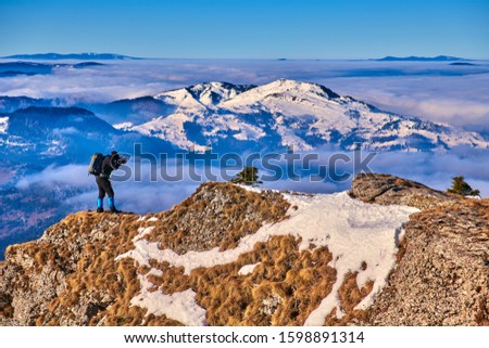 Nature photographer in the action.Professional photographer outdoor in winter,Landscape view from Ceahlău Mountains National Park