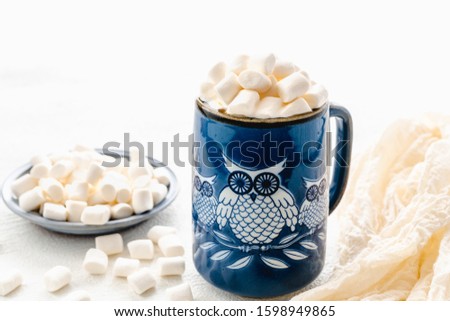 Marshmallow and coffee. Owl-shaped ceramic mug with marshmallows close up on white background, copy space