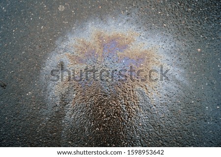 Photo of a background with a multi-colored rainbow stain of gasoline on asphalt
