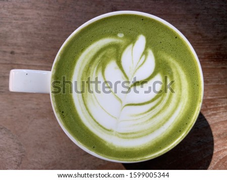 Top view and close up white cup of coffee on table on topping leaf shaped bubble cream and light and shadow.