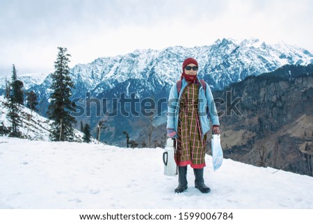 Portrait of Himachal  pradesh  woman holding kettle to serve hot tea and coffee with beautiful snow mountain landscapes in the background, tourist season. 