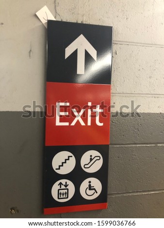 Exit sign with symbols of stairs, escalators, elevators, and handicap accessible transportation