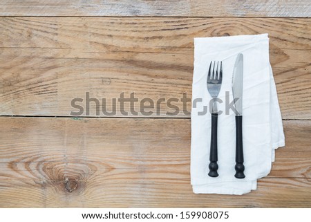 Cutlery and napkin on wooden background
