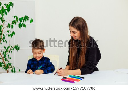 mother and young son draws a picture at the table