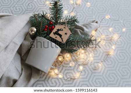 Christmas and New Year composition. light cup on a gray background with fir branches and Christmas lights. Winter card. Soft focus
