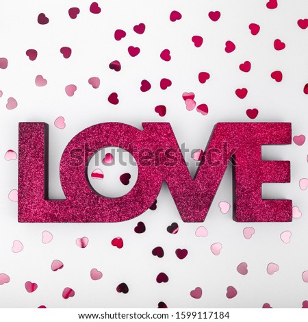 Dark red sign LOVE and glitter heart confetti. Valentine day concept. Trendy minimalistic flat lay design background. Square