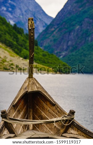 Old wooden viking boat on fjord shore. Mountains and Sognefjord. Tourism and traveling concept